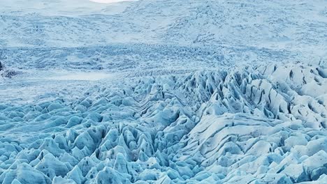 Aerial-landscape-view-of-textured-ice-formations-of-a-glacier-in-Iceland,-at-dusk