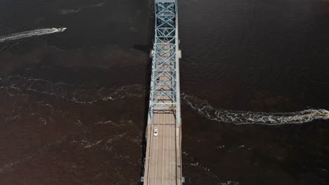 Lanchas-Rápidas-Pasando-Por-Una-Vista-Aérea-De-Drones-Del-Centro-De-Jacksonville-Con-Vista-Al-Puente-Con-Autos-Pasando-Por-Nubes-Blancas-De-Agua