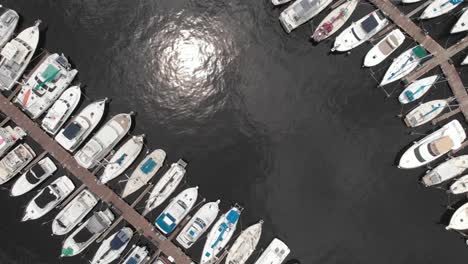 Aerial-drone-shot-overlooking-boats-in-the-water-marina-speedboat-passing-by-in-water-sailboat-vessel-fisherman-blue-sky-white-clouds