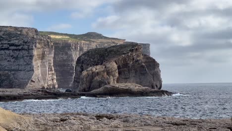 4K-Handheld-Shot-Capturing-the-Rustic-Shoreline-Beauty-of-Dwejra-Bay,-Gozo-Island,-Malta:-Waves-of-the-Mediterranean-Sea-Crashing-Against-Iconic-Rocky-Formations-in-a-Picturesque-Setting