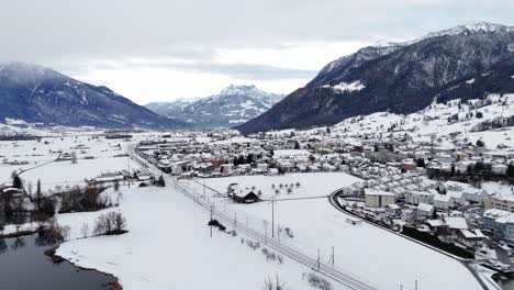 Aerial-approach9ng-shot-of-swiss-Village-named-Reichenburg-and-mountain-range-during-snowy-winter-day-in-Switzerland