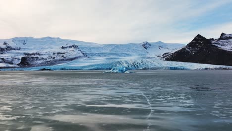 Vista-Panorámica-Aérea-Del-Paisaje-De-Un-Glaciar-Con-Formaciones-De-Hielo-Texturizadas,-En-Islandia,-Al-Atardecer