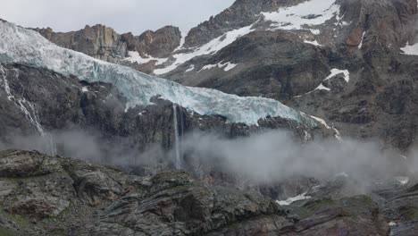 Fellaria-glacier-in-the-mountains-of-Italy,-with-meltwater-waterfalls-and-fog