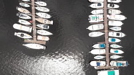 Aerial-zoom-out-of-boats-in-the-marina-docked-in-water-brackish-water-white-boats-sun-reflecting-in-water