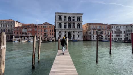 Toma-De-Seguimiento-De-4k:-Joven-Turista-Acercándose-Al-Gran-Canal-Desde-Una-Calle-Estrecha-En-Venecia,-Italia