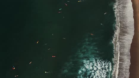 Dozens-of-surfers-catching-waves-in-Puerto-Escondido,-Mexico-from-above