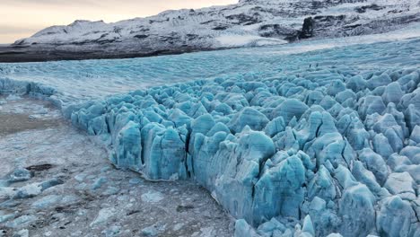 Vista-Aérea-Del-Paisaje-Sobre-Formaciones-De-Hielo-Texturizadas-De-Un-Glaciar-En-Islandia,-Al-Atardecer