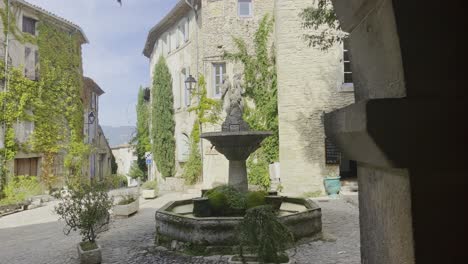 Beautiful-little-romantic-square-with-fountain-and-figure-pillar-with-old-French-houses-in-the-background-in-good-weather