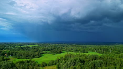 Stormy-rain-clouds-flowing-above-green-forestry-flatlands-of-Latvia,-aerial-view