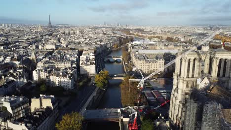 Drone-passes-next-to-Notre-Dame-Church,-showing-River-Seine-and-Eiffel-Tower-in-the-background