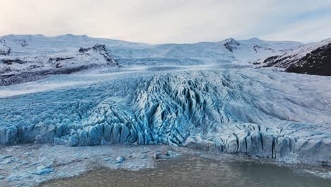 Aerial-view-of-a-glacier-with-textured-ice-formations,-in-Iceland,-at-dusk