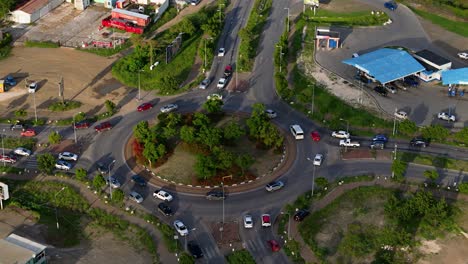 Aerial-orbit-around-busy-traffic-circle-roundabout-on-Caribbean-island-with-cars-circling-and-exiting
