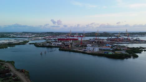 Panoramic-aerial-of-Industrial-seaport-with-loading-cranes-and-docks-at-sunset