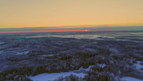 Red-sunset-or-sunrise-over-harsh-winter-landscape,-aerial-drone-view
