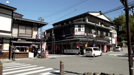 Ein-Tag-In-Den-Straßen-Von-Takayama,-Japan,-Während-Menschen-Auf-Den-Bürgersteigen-Spazieren-Gehen-Und-Flanieren-Und-Autos-Durch-Die-Alleen-Fahren,-Die-Von-Geschäften-Und-Restaurants-Umgeben-Sind