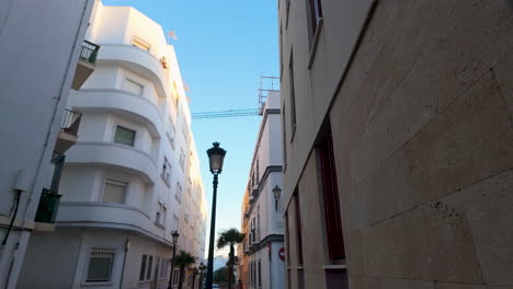 Narrow-alley-between-white-Mediterranean-buildings---Cadiz,-Spain