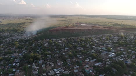 Fesselnde-4K-Luftaufnahmen-Zeigen-Eine-Dynamische-Push-in-Drohnenaufnahme,-Die-Nahtlos-Ein-Ländliches-Township-Dorf-Am-Rande-Einer-Abfallverarbeitungsanlage-In-Südafrika-Zeigt
