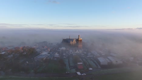 Aerial-drone-view-of-church-foggy-morning,-Workum,-Friesland,-Netherlands
