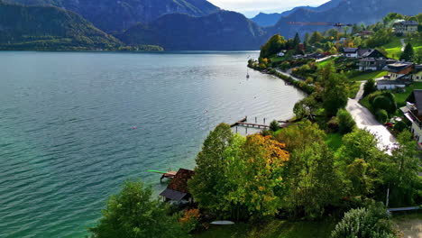Beautiful-small-town-on-lake-coast-surrounded-with-mountains,-aerial-view