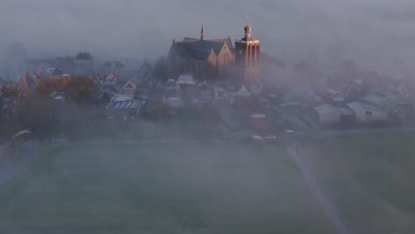 Aerial-drone-view-of-church-foggy-morning,-Workum,-Friesland,-Netherlands