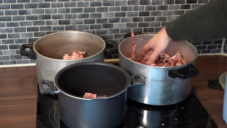Hand-arranging-raw-beef-bones-in-various-pots-for-boiling-bone-broth