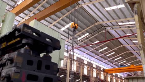 Production-area-on-manufacturing-factory-with-stack-of-iron-molding,-overhead-crane-and-big-machine