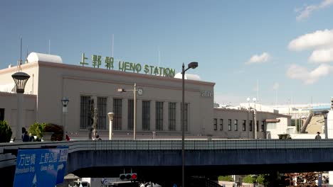 Edificio-De-La-Estación-De-Ueno-Con-Señalización-Verde-En-La-Parte-Superior-Visto-Desde-Una-Pasarela-Elevada-En-Un-Día-Soleado