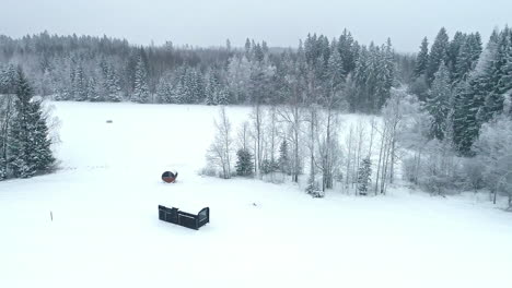 Aerial-view-of-a-solitary-hut-in-a-snow-covered-forest-clearing-in-a-winter-landscape
