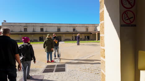Visitantes-Que-Entran-En-Un-Edificio-Histórico-En-Cádiz,-España,-Con-Un-Patio-Iluminado-Por-El-Sol
