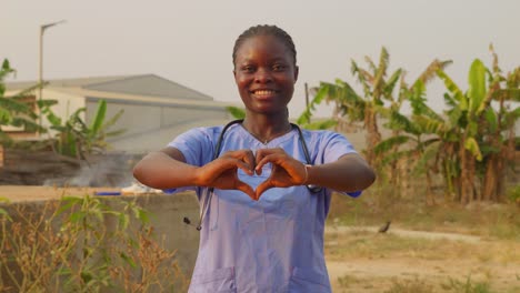 Porträt-Einer-Afrikanischen-Ärztin-Und-Krankenschwester,-Die-Mit-Handgesten-„Ich-Liebe-Dich“-Sagt,-Während-Sie-In-Zeitlupe-Vor-Der-Kamera-Lächelt