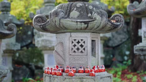 Daruma-Dolls-on-Shrine-Stone-Lantern-at-Katsuoji-Temple,-Minoh-Japan