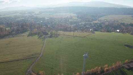 Windkraftanlagen-An-Einem-Sonnigen-Tag-In-Der-Nähe-Des-Dorfes,-Umgeben-Von-Einer-Wiese
