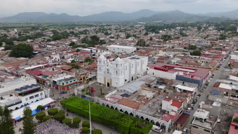 Aerial-establishing-shot-of-Tecalitlan-City-with-white-temple-and-cityscape-in-Mexico---Mountain-range-in-background