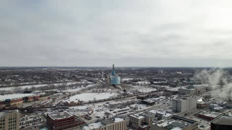 Downtown-Winnipeg-in-winter-with-Human-Rights-Museum,-The-Forks-and-trains,-4K-aerial