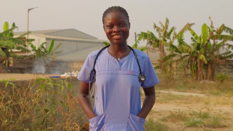 African-female-nurse-doctor-with-stethoscope-laughing-smiling-n-front-of-camera-in-clinic-hospital-of-Africa-with-palm-tree-village-remote-background
