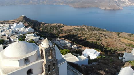 Vista-De-Drones-En-Grecia-Volando-Sobre-Una-Iglesia-Blanca-En-Una-Colina-Con-Una-Casa-Blanca-Griega-Frente-Al-Mar-Azul-En-Una-Montaña