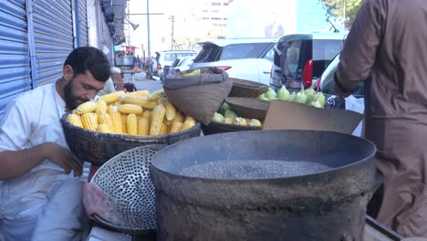 Closeup-cinematic-shot-of-a-shopkeeper-selling-roasted-corns-at-a-roadside-stall-in-Saddar-Bazar-Street-of-Karachi,-Pakistan-during-sunset