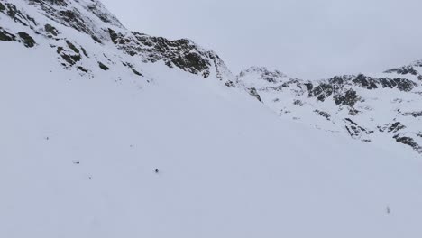 Persona-Desde-Lejos-Esquiando-Por-Una-Gran-Pendiente-Nevada-En-Montañas-Alpinas