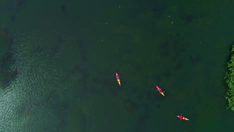 Aerial-Drone-Fly-Above-Tropical-Green-Sea-Bay-with-Red-Yellow-Canoes-Paddling