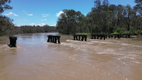 Low-pan-drone-of-flooded-Goulburn-river-with-old-bridge-in-strong-racing-currents