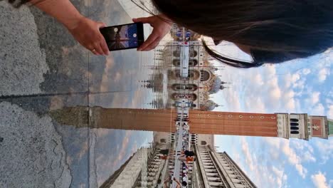 Toma-Vertical-De-Una-Creadora-De-Contenido-Filmando-Y-Fotografiando-El-Campanile,-Venecia.