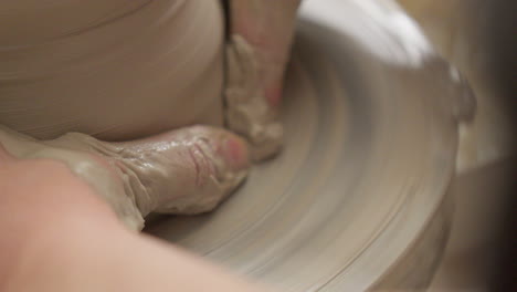 Close-up-skilled-artisan-smoothing-out-the-walls-of-a-vase-delicately-with-her-hands-on-the-potters-wheel
