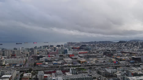 Aerial-panoramic-shot-of-San-Francisco-Cityscape-with-ships-on-sea-during-cloudy-day---Traffic-on-main-road-in-town