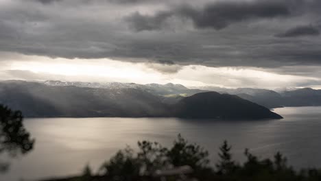 Densas-Nubes-Tormentosas-Atravesadas-Por-Rayos-De-Sol-Son-Transportadas-Por-El-Fuerte-Viento-Sobre-El-Oscuro-Fiordo-Y-Las-Montañas-De-Hardanger