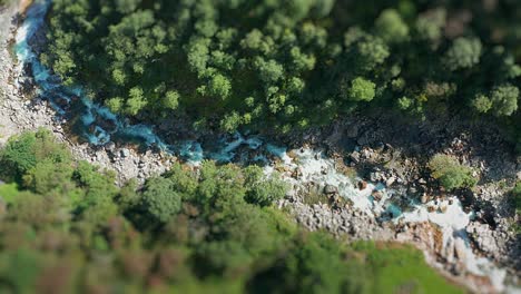 A-narrow-rocky-canyon-with-a-shallow-mountain-river-winds-between-forest-covered-cliffs