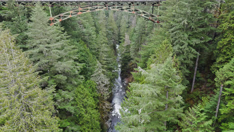 4K-drone-footage-approaching-bridge-over-river-and-evergreen-forest
