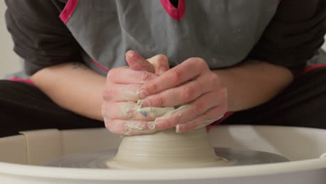 Ceramic-artist-centering-clay-on-potters-wheel-delicately-with-her-hands,-mid-shot
