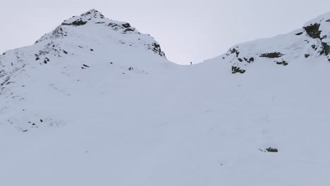 Person-starting-to-ski-down-a-large-snowy-mountain