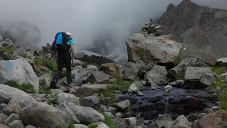 Young-Caucasian-male-hiker-walks-through-boulder-field-in-the-Italian-Alps-into-fog