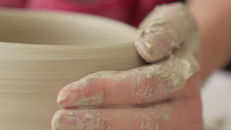 Pottery-artist-smoothing-the-walls-of-a-bowl-on-a-throwing-wheel-with-both-hands